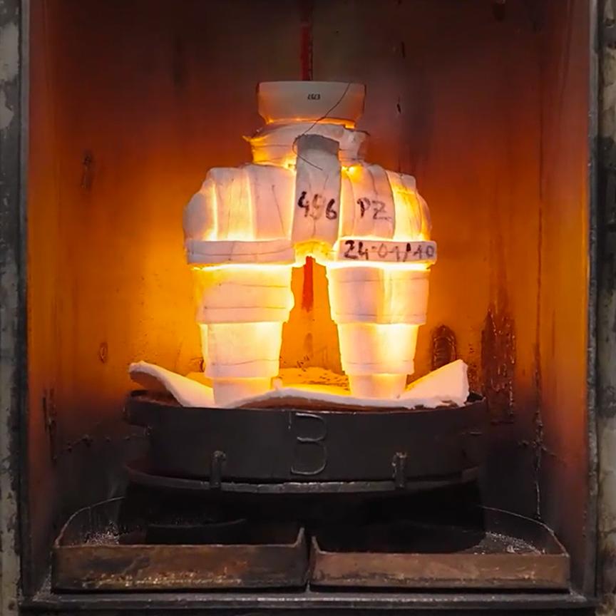 L’immagine mostra un modello di cera ricoperto da vari strati di polvere ceramica e liquido all’interno di un forno. Questo processo consente alla cera di sciogliersi, lasciando dietro di sé lo stampo di pressofusione vero e proprio.