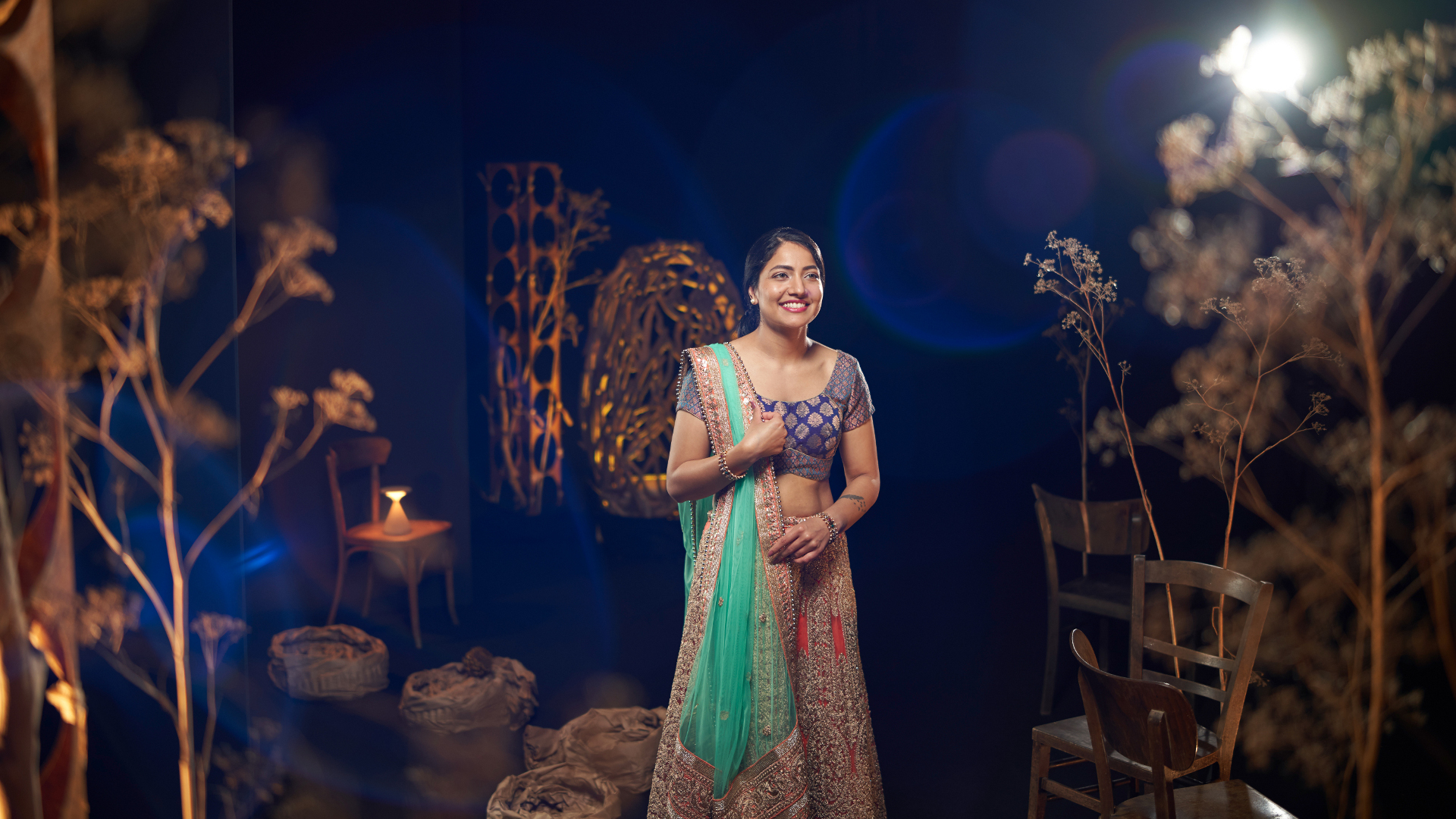 A woman in traditional attire standing gracefully in an artistically lit set, captured with the clarity and precision of ZEISS optics.