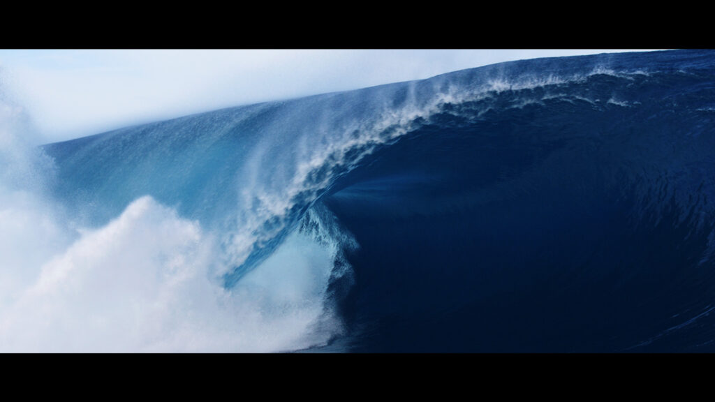 A powerful ocean wave curls and crashes, captured in sharp detail with vibrant blue tones.