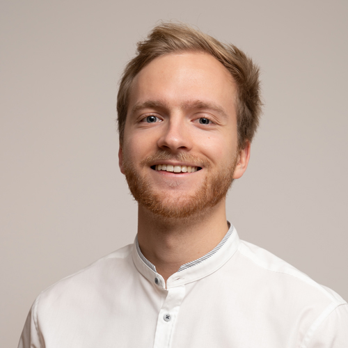 A smiling professional wearing a white shirt, embodying expertise and approachability for the ZEISS team.