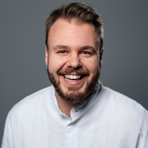 A smiling professional wearing a white shirt, embodying expertise and approachability for the ZEISS team.