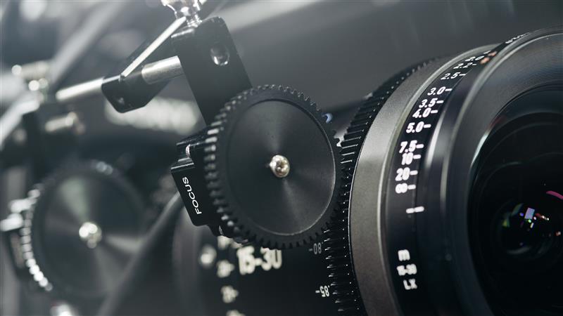 Close-up view of a professional camera setup featuring a ZEISS cine lens with focus and aperture adjustment gears.
