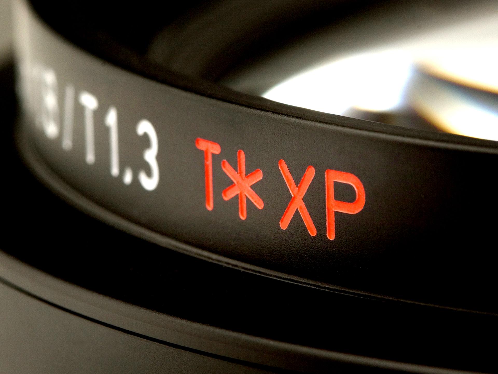 Close-up of a ZEISS camera lens showing the engraved text "T* XP" and "T1.3" on the lens barrel.