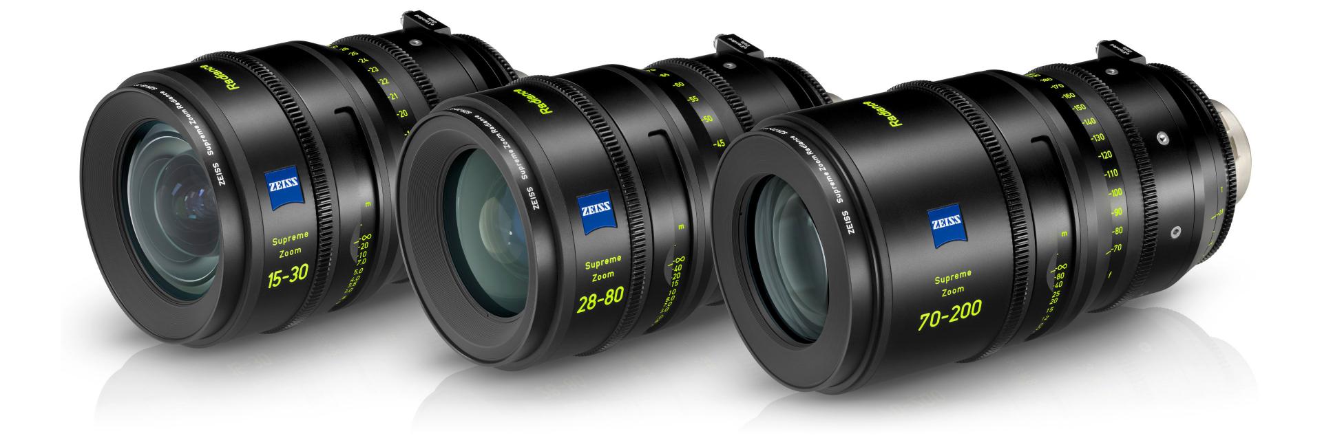 Three black ZEISS Supreme Prime Radiance camera lenses with yellow and white markings are displayed lying on a white background.