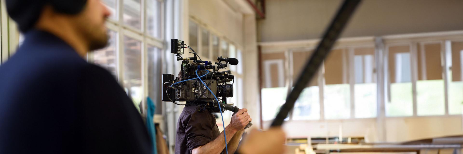 A professional cameraman operating a high-end film camera equipped with advanced technology on set.