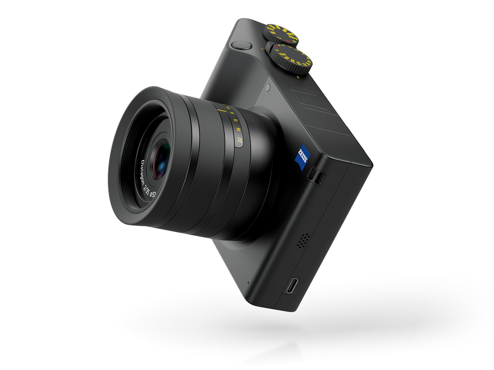 Black compact digital camera with a ZEISS lens and control dials, shown floating against a white background.