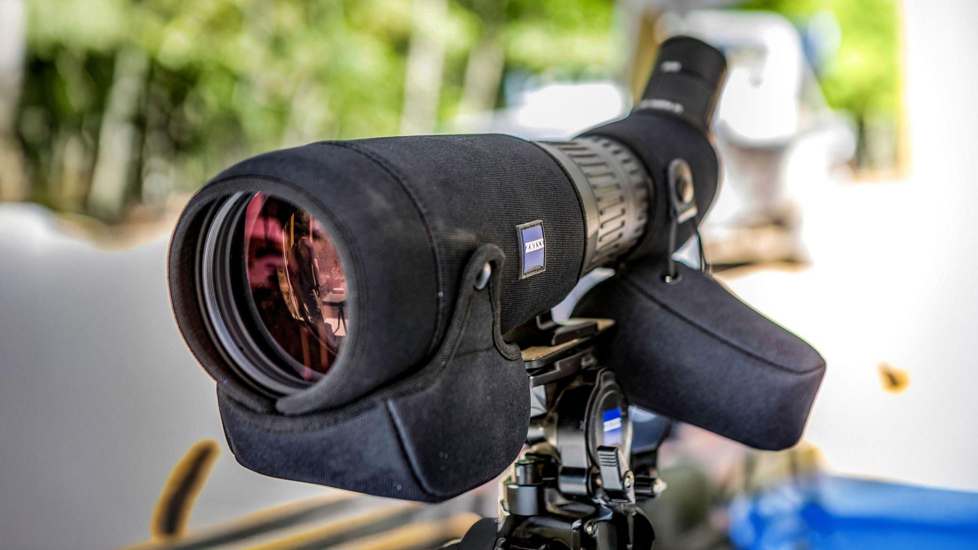 Close-up view of a ZEISS spotting scope mounted on a tripod, set up outdoors with a blurred natural background.