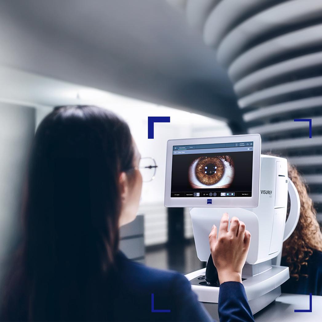 Un ottico donna guarda lo schermo di ZEISS VISUREF 600 che mostra l&apos;immagine di un occhio.