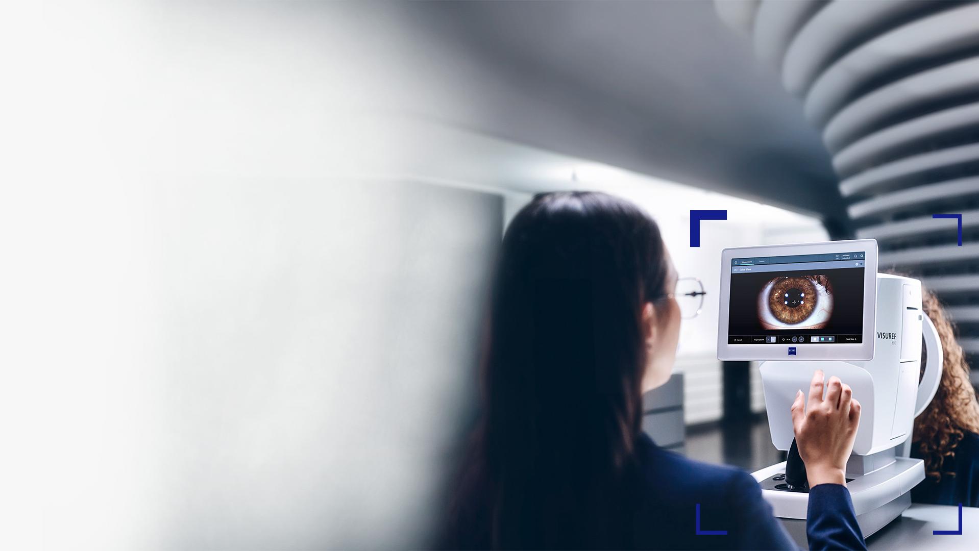 Un ottico donna guarda lo schermo di ZEISS VISUREF 600 che mostra l&apos;immagine di un occhio.