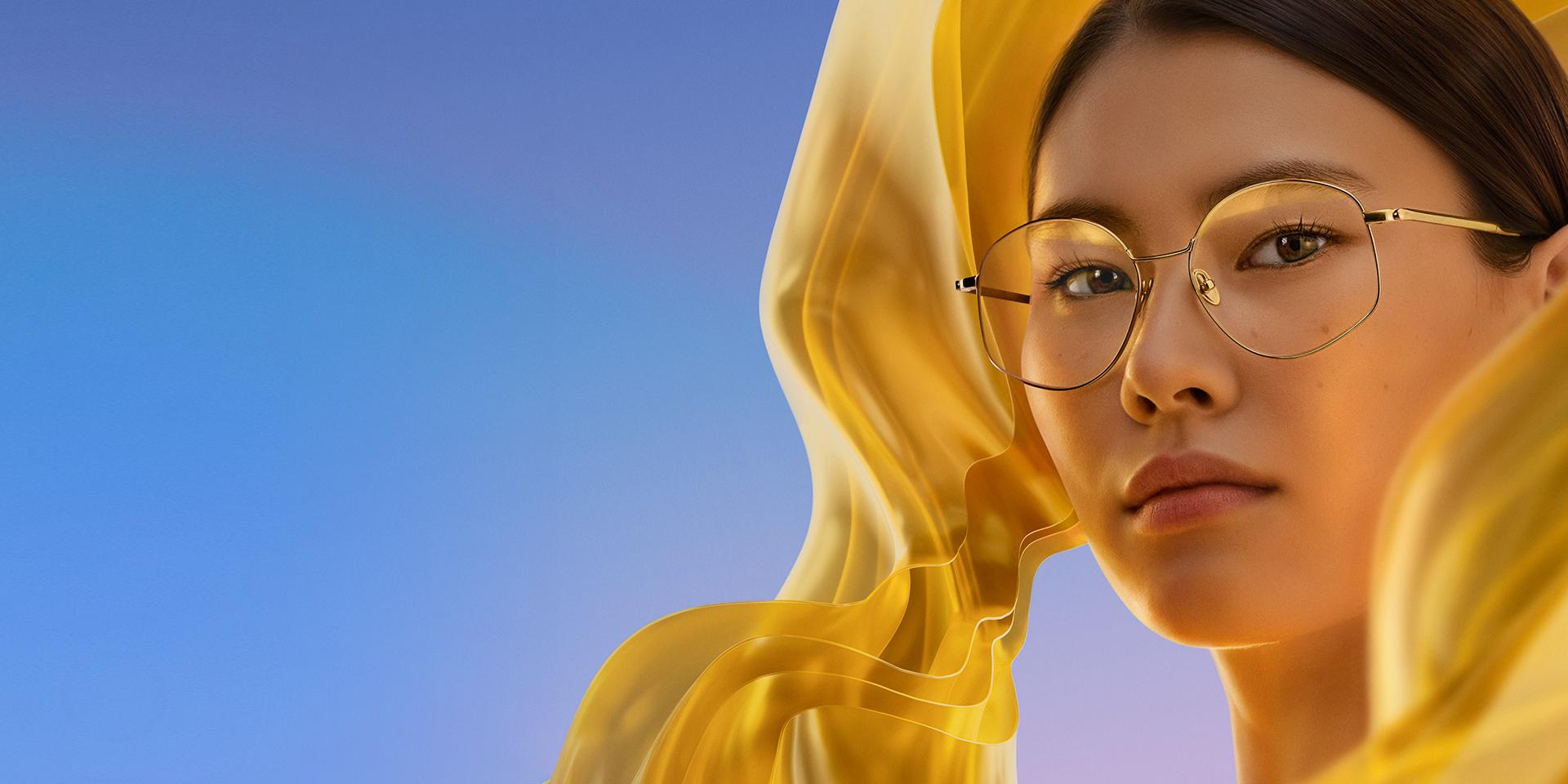 Donna che indossa occhiali da vista con ZEISS DuraVision Gold UV, che aggiunge un sottile ma distintivo riflesso dorato alle lenti.