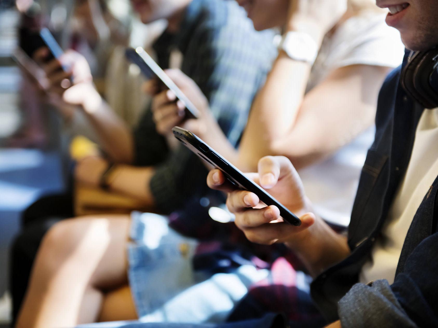 Gli smartphone emettono alti livelli di luce blu. Sono raffigurate diverse persone che guardano gli smartphone. 