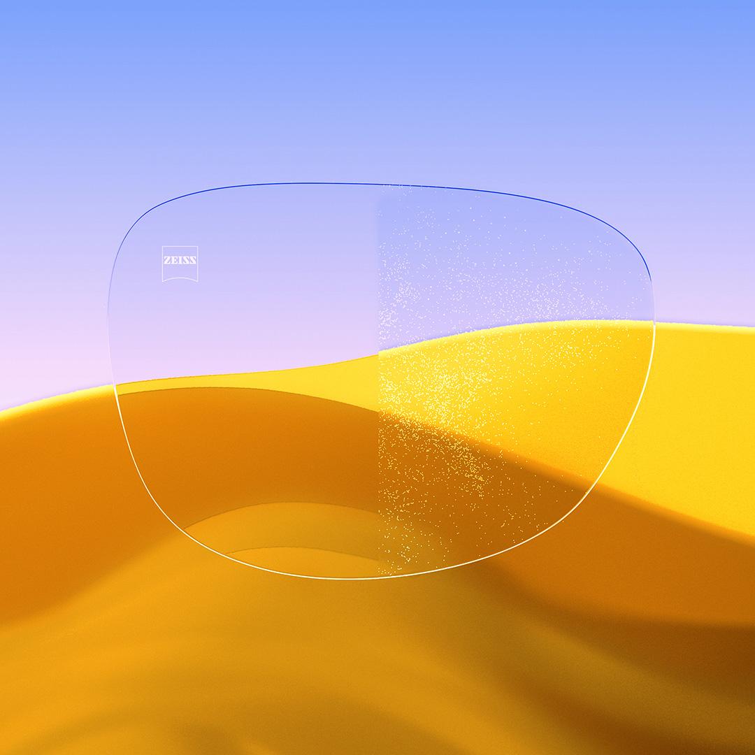 Lente per occhiali divisa, con un lato con trattamento ZEISS DuraVision Gold UV chiaro e pulito, e l'altro lato con polvere che la ricopre.