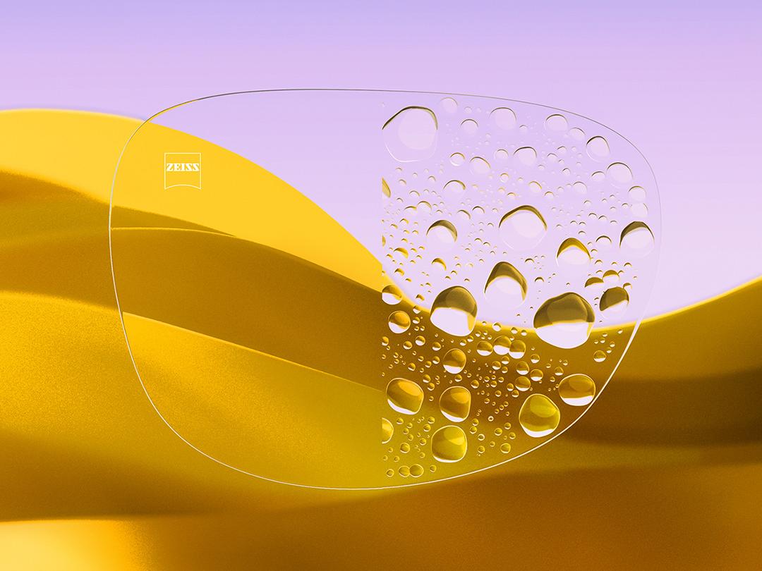 Lente per occhiali divisa, con un lato con trattamento ZEISS DuraVision Gold UV chiaro e pulito, e l'altro lato con gocce d'acqua.