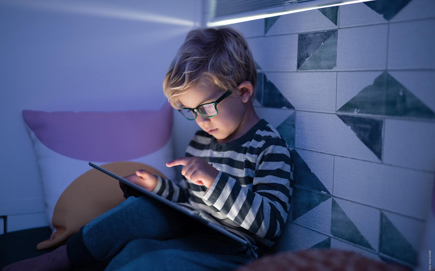 Due bambine felici e carine che giocano su un dispositivo informatico tablet in biblioteca a scuola. Concetto di tecnologia wireless per l&apos;istruzione e l&apos;autoapprendimento. Stili di vita e amicizia tra persone. Bambini in età prescolare