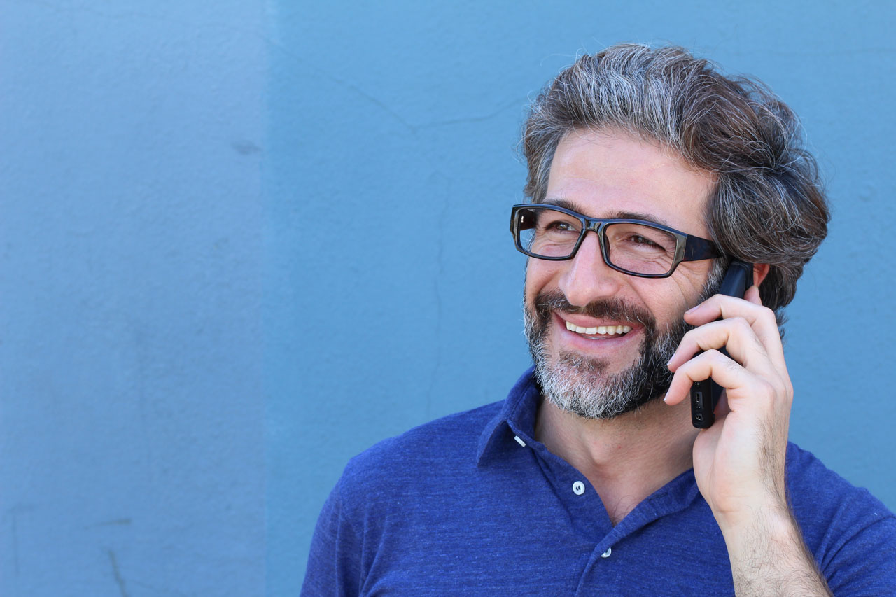 Un uomo con gli occhiali parla al cellulare
