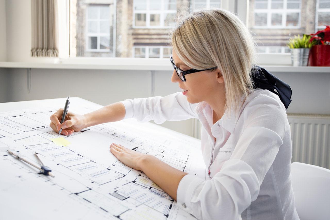 Giovane architetto donna con occhiali al lavoro su un progetto