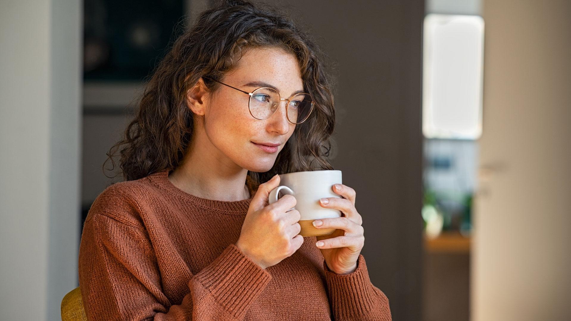 Ragazza con occhiali da vista che beve una bevanda calda