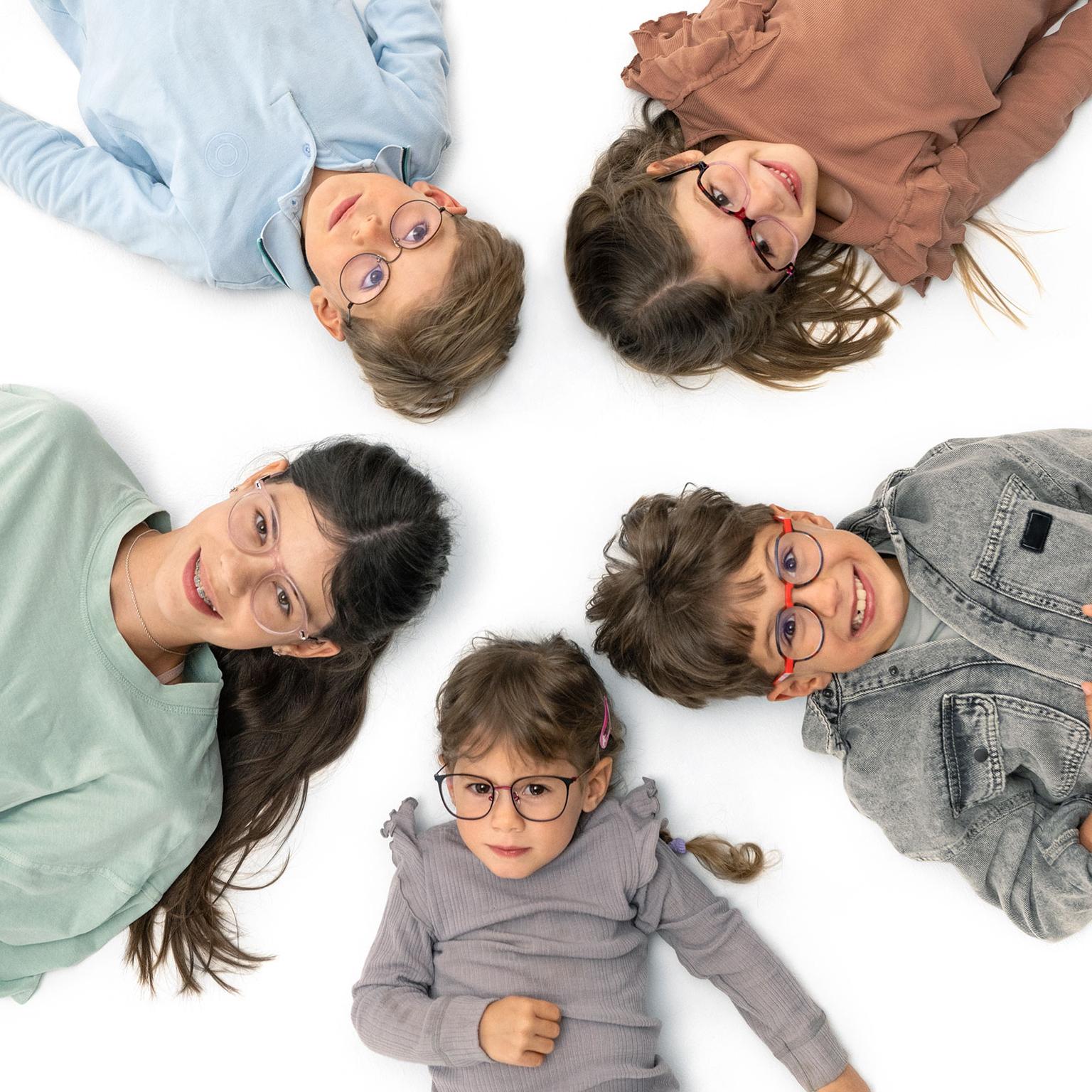 Gruppo di bambini con gli occhiali sdraiati allegramente in cerchio