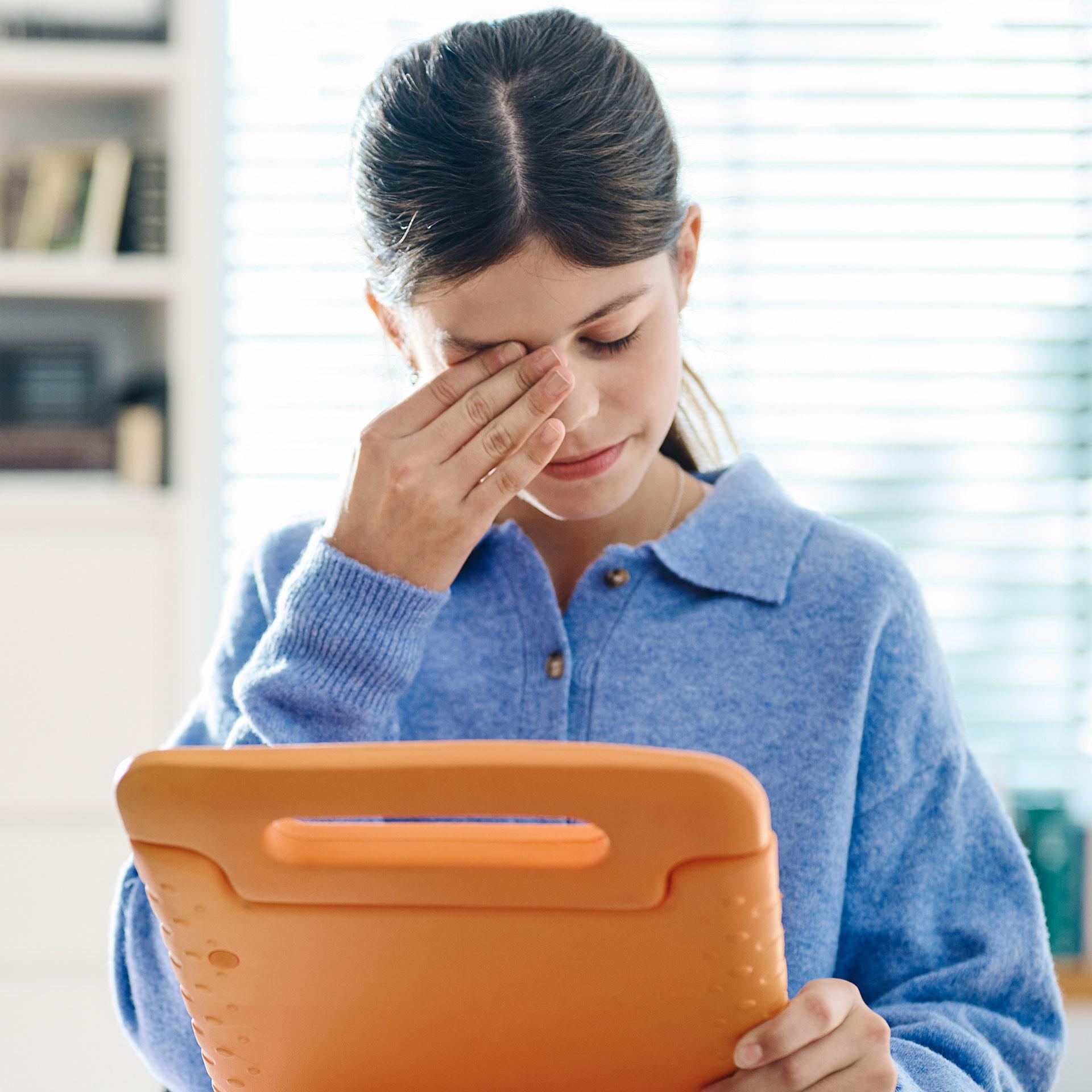 Ragazza con tablet che mette una mano sul viso