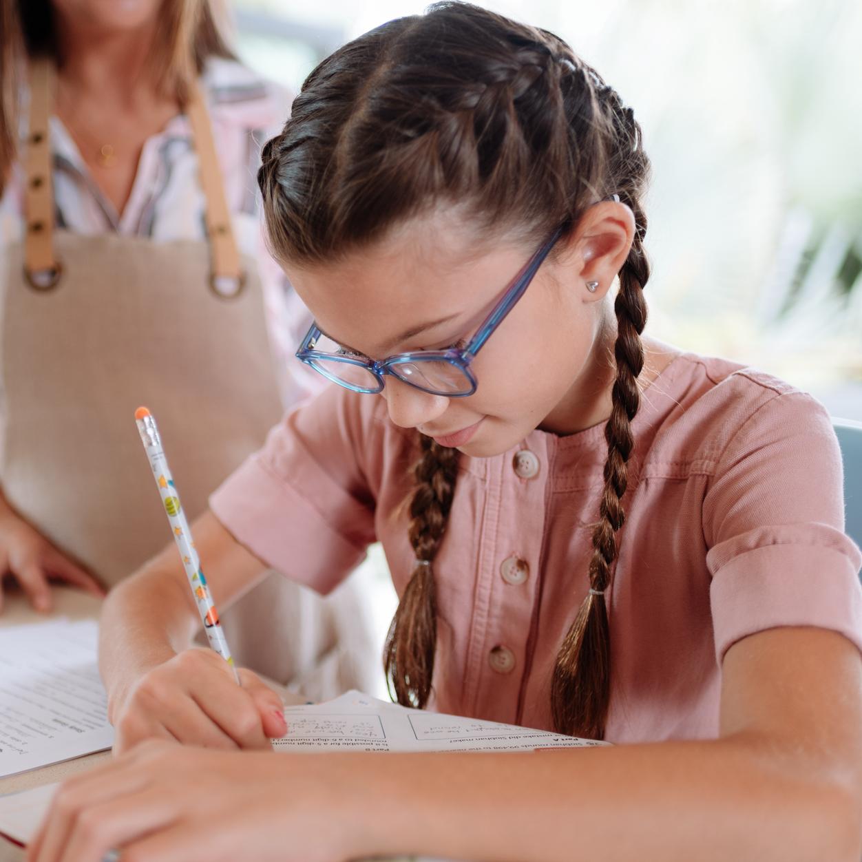 Ragazza con gli occhiali che scrive con una penna