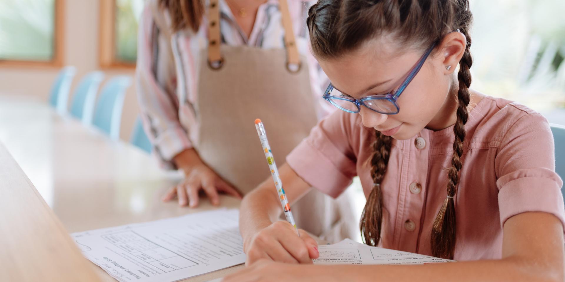 Ragazza con gli occhiali che scrive con una penna