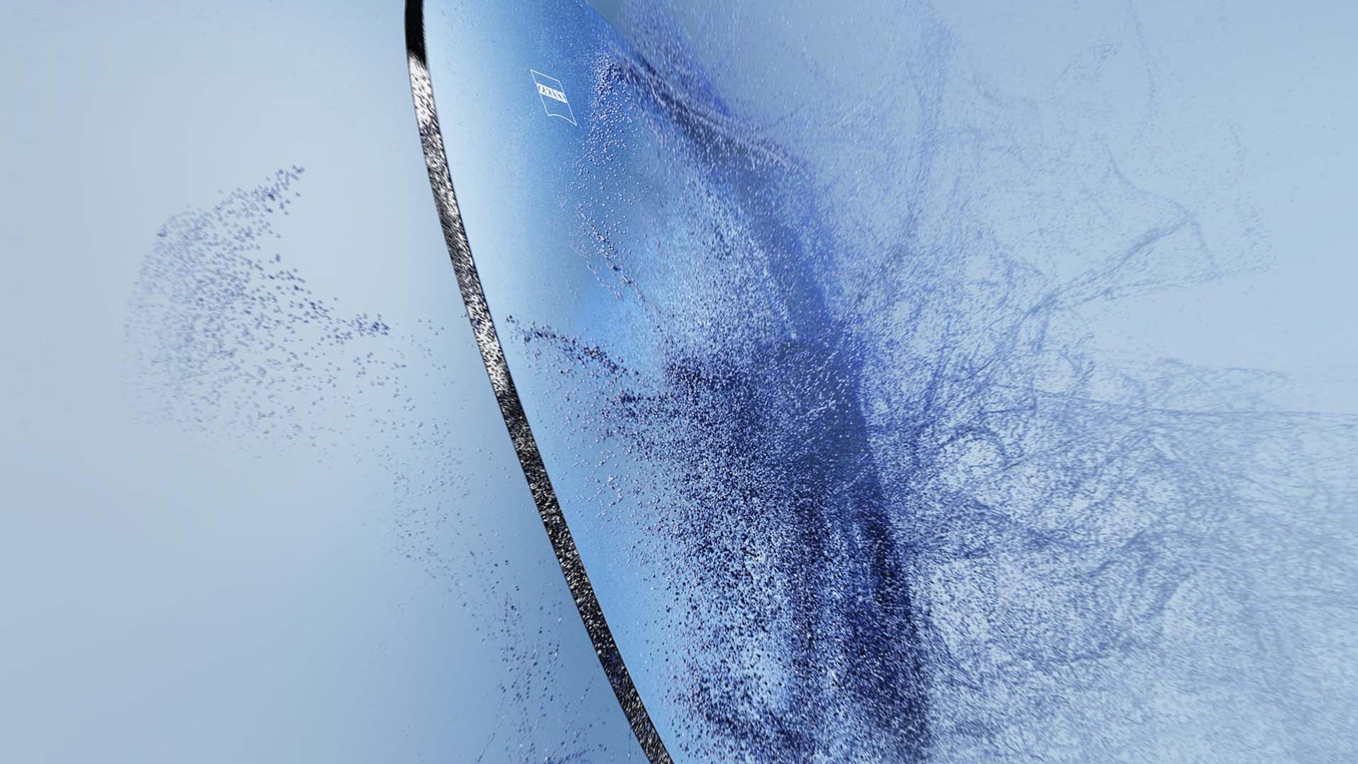 Una lente per occhiali da vista con logo ZEISS si scontra con la sabbia.
