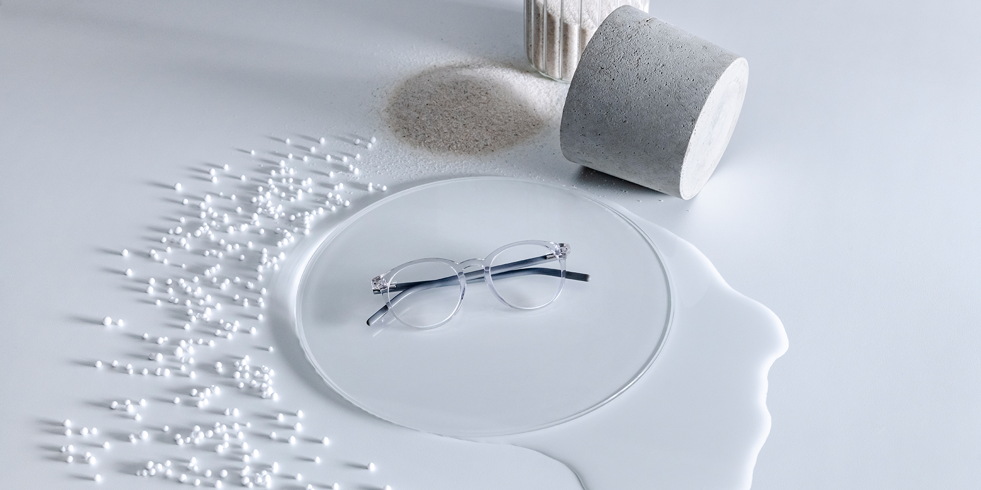 Lenti ZEISS con trattamento DuraVision® collocate su una base in vetro circondata da acqua, sabbia, perline e una pietra.