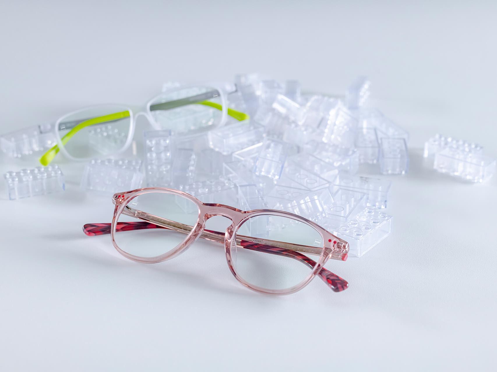 Due paia di occhiali per bambini con lenti ZEISS e trattamenti per bambini DuraVision®. Gli occhiali sono posti tra mattoncini trasparenti per bambini.