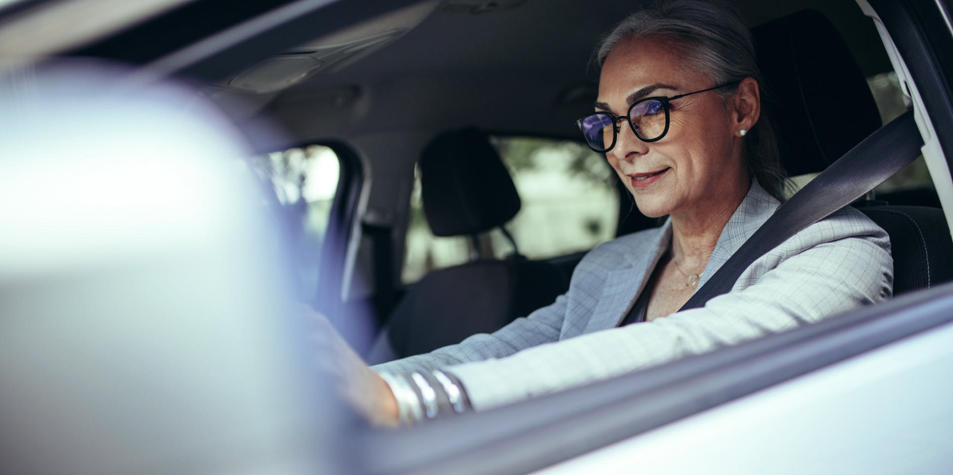Donna matura in un'auto che indossa occhiali con lenti ZEISS DriveSafe.