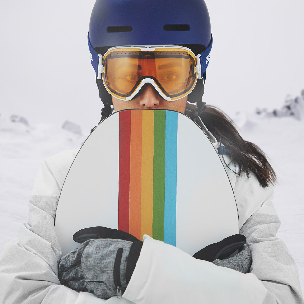 A woman wears a blue helmet and ZEISS ski goggles with transparent visor.