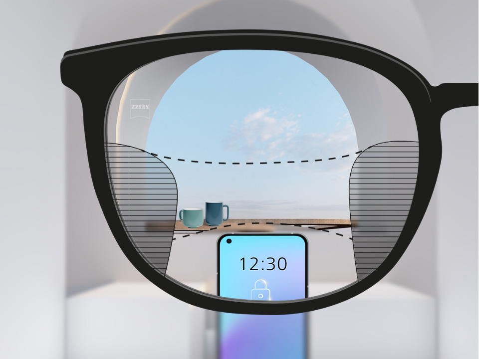 Immagine delle lenti ZEISS Progressive SmartLife con uno smartphone, tazze sullo sfondo, lente completamente chiara con sottili sfocature a sinistra e a destra.