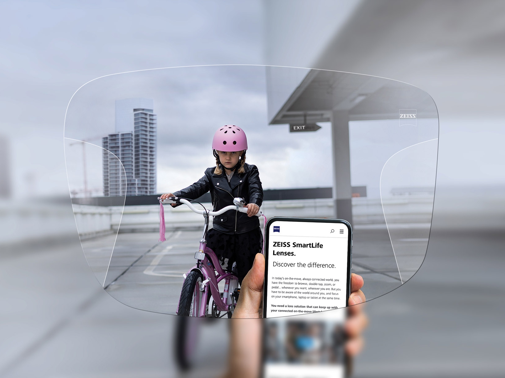 Persona che guarda il suo telefono attraverso le lenti progressive ZEISS SmartLife. Sullo sfondo si vede una ragazza in bicicletta che indossa un casco rosa. 