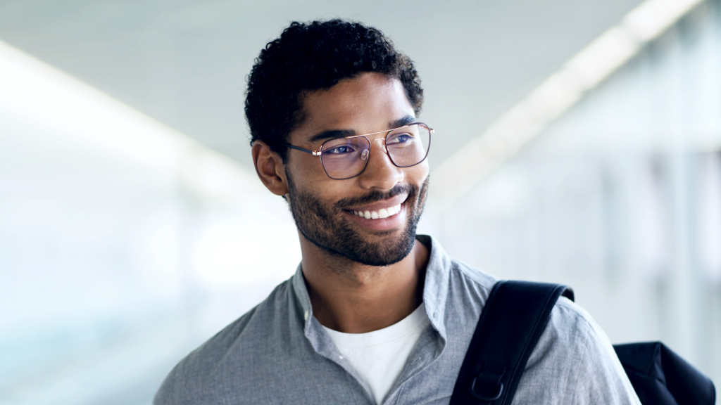 Un ragazzo sorridente con uno zaino in spalla che indossa occhiali digitali ZEISS SmartLife e guarda in diagonale.